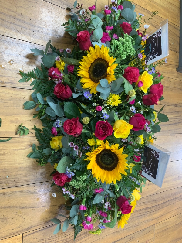 Bright garden style casket tribute